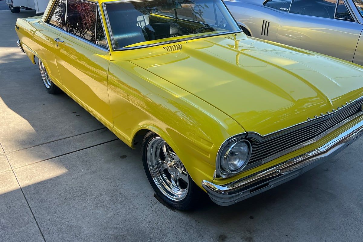 Yellow classic Chevrolet coupe on a concrete driveway