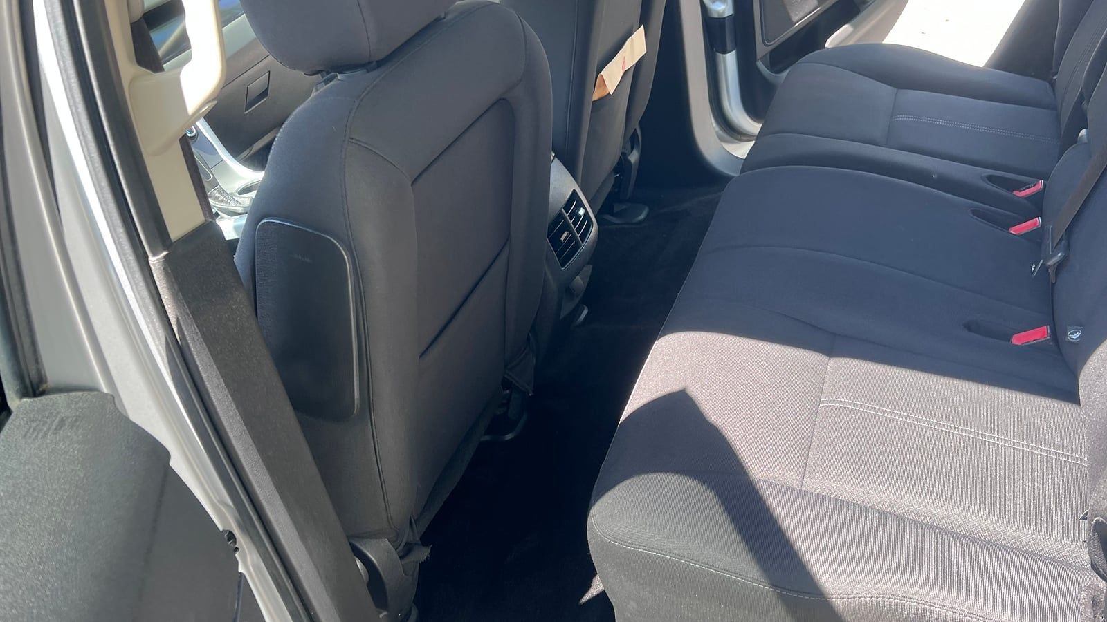 Rear cloth bench seat and carpet of a silver Ford SUV seen through the open door