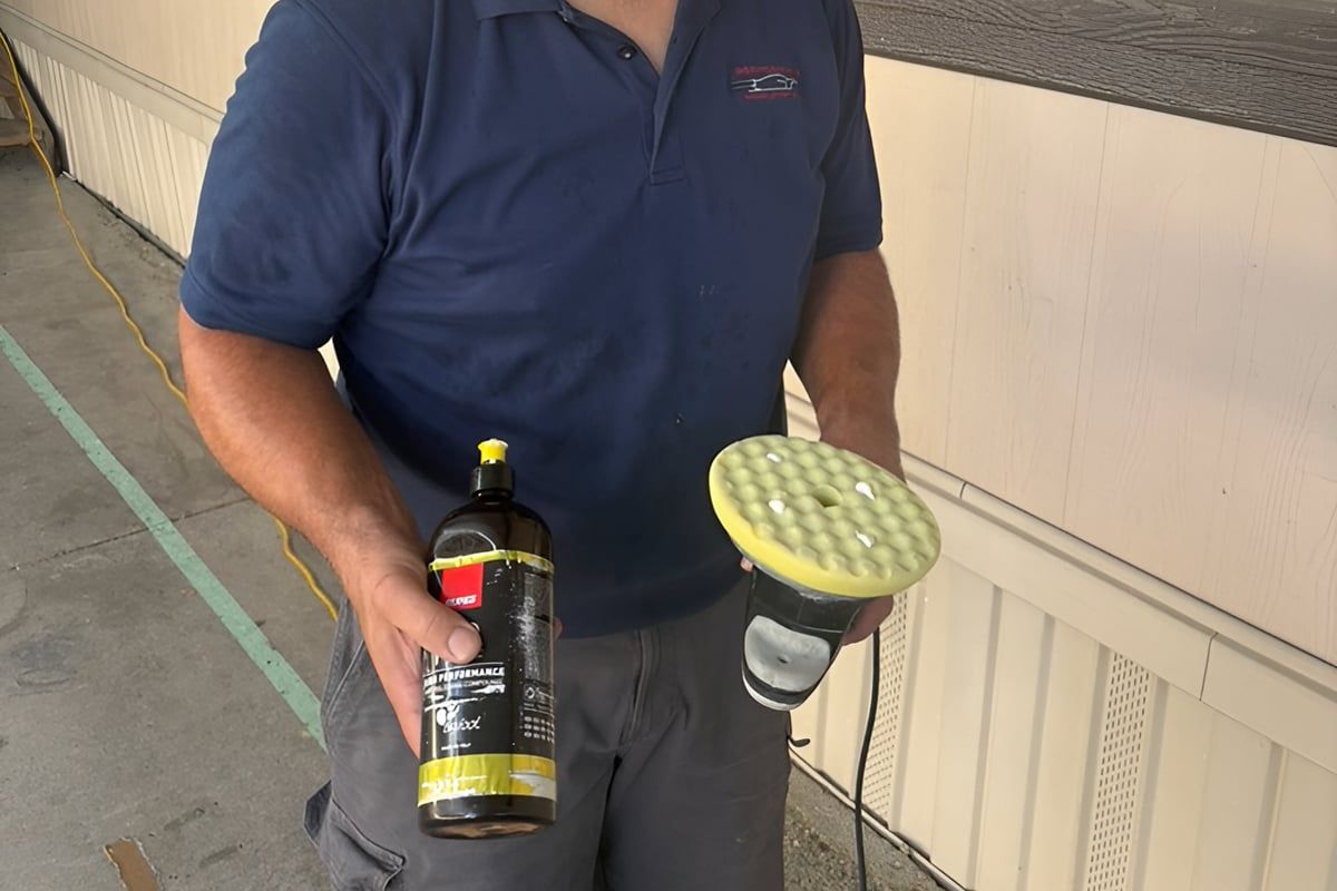 Hands holding a polishing compound bottle and a polisher with a yellow foam pad