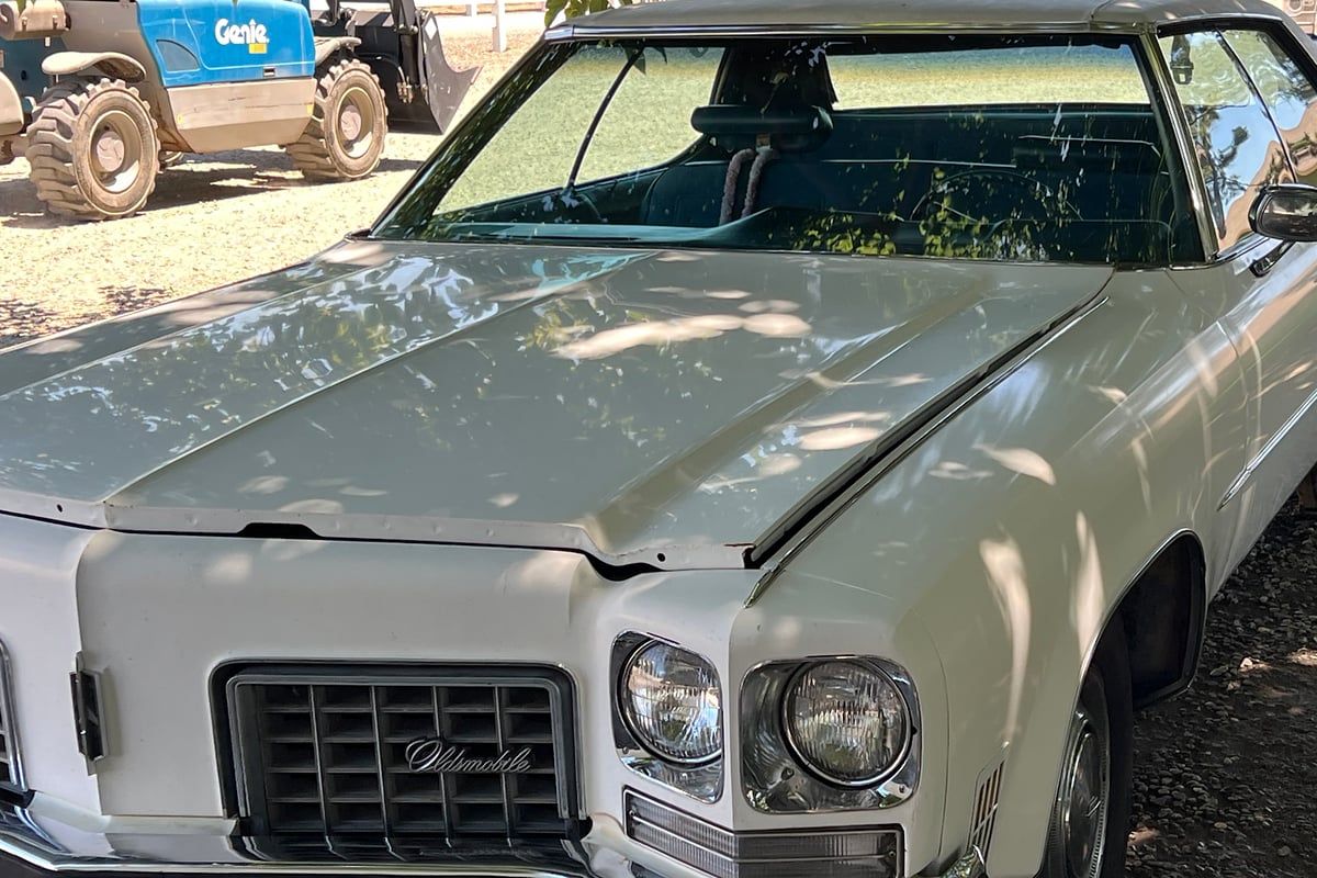 Front of the same white Oldsmobile with a clean hood, windshield and grille